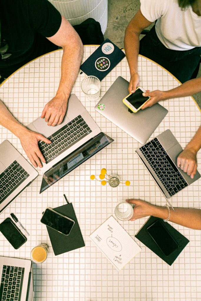 Mastering the First Impression: Your intriguing post title goes here Top view of a team collaborating with laptops, phones, and notes in a modern office.
